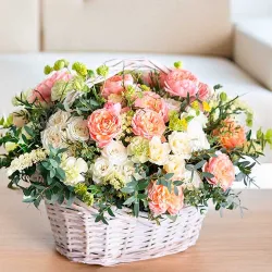 Arreglo de rosas de jardín hecho con cesta de mimbre blanca