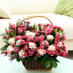 Arreglo floral de rosas, claveles y flores de cera hecho en una cesta de mimbre