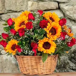 Cesta de mimbre con girasoles y rosas rojas.